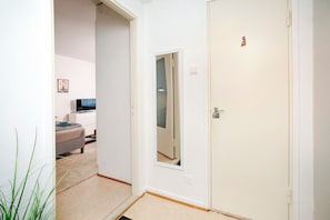 A hallway with a bed, a dresser, and a television in a room.