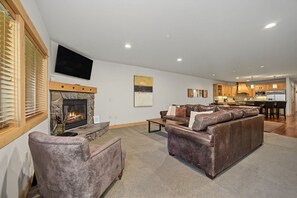 A living room with a fireplace, a sofa, a coffee table, and a television mounted on the wall.