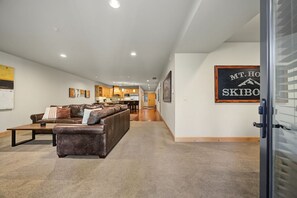 A spacious hallway with a leather sofa, a dining area, and a kitchen in the background.