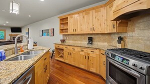 Eine moderne Küche mit Holzausstattung, Granitarbeitsplatten, einem Edelstahlspülbecken und einem eingebauten Backofen.