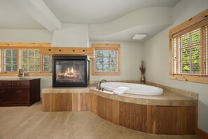 Un baño con chimenea integrada, bañera independiente y paneles de madera.