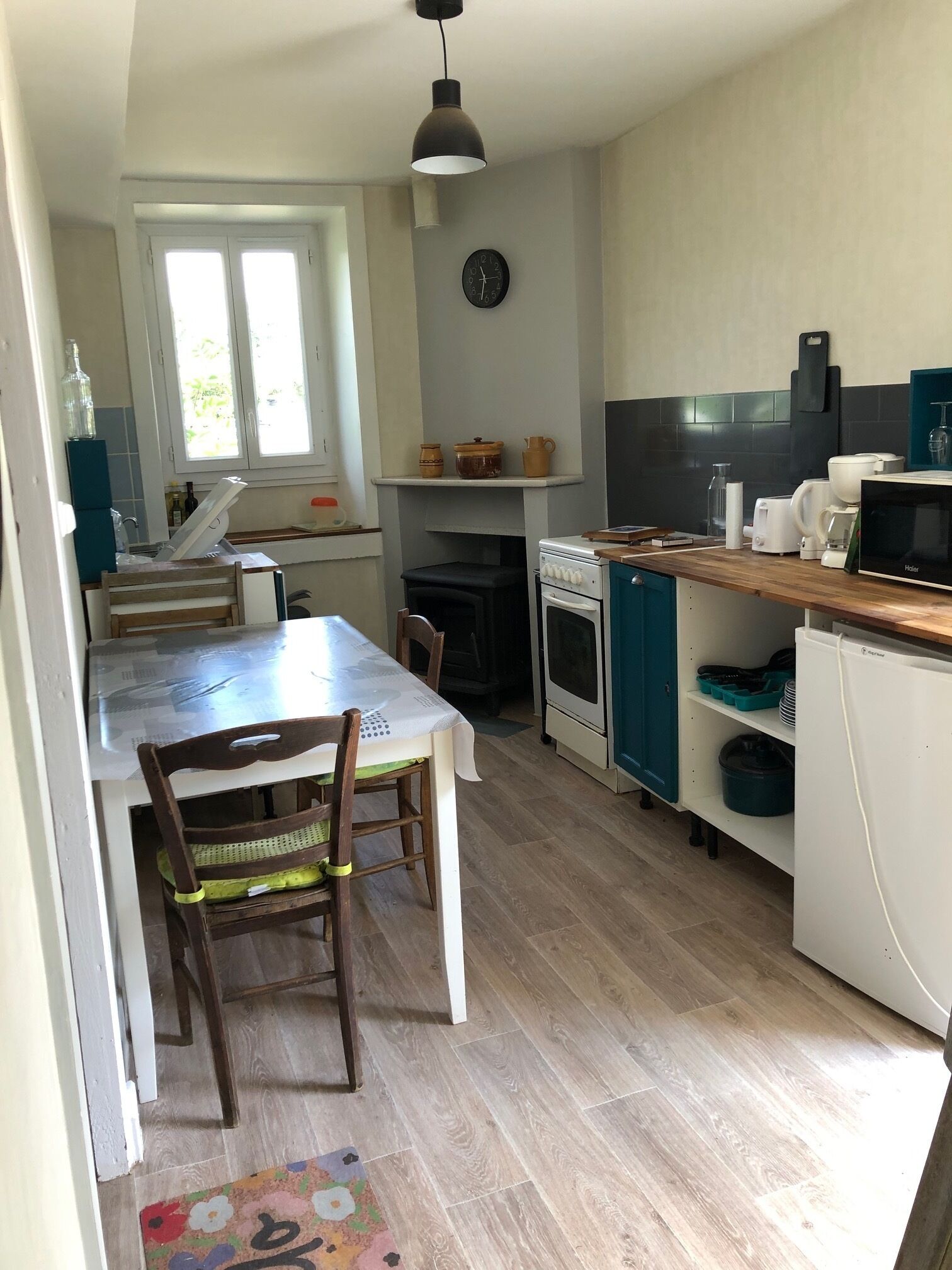 Une cuisine compacte comprenant une table à manger, des chaises, une cuisinière et un four à micro-ondes.
