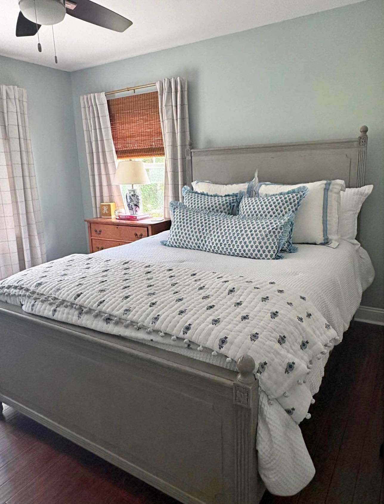 A bedroom with a bed, a nightstand, a lamp, and a window with curtains.