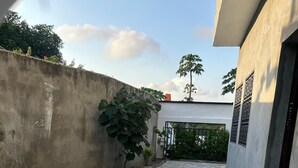 Une cour avec un sol carrelé, un mur en béton et un bâtiment doté d’une porte.