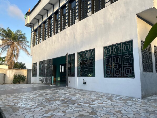 A building with a tiled entrance area and patterned window grills.