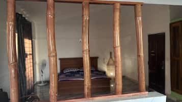 A room with a bed, a bedside table, and a window with bamboo blinds.