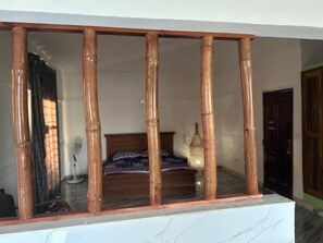 A room with a bed, a bedside table, and a window with bamboo blinds.