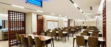 A spacious dining area with multiple tables and chairs, a ceiling with recessed lighting, and a decorative partition.