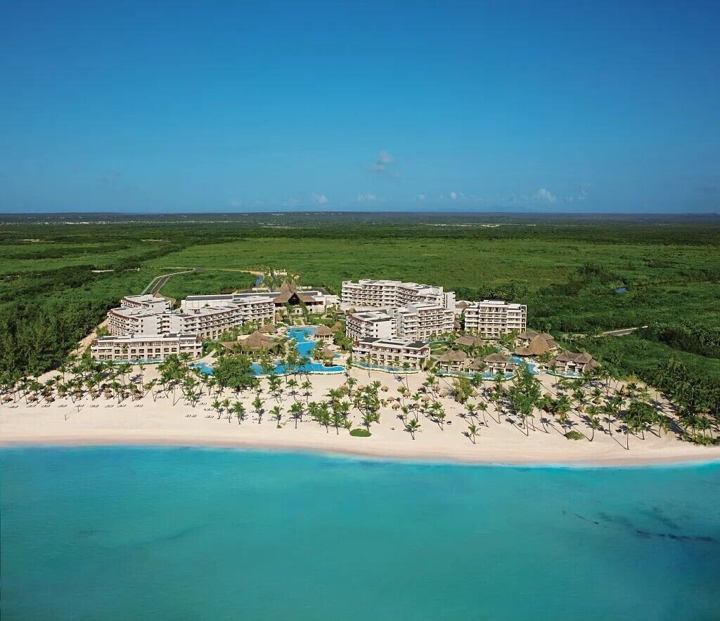 A resort with multiple buildings, a beach, and a clear blue sky.