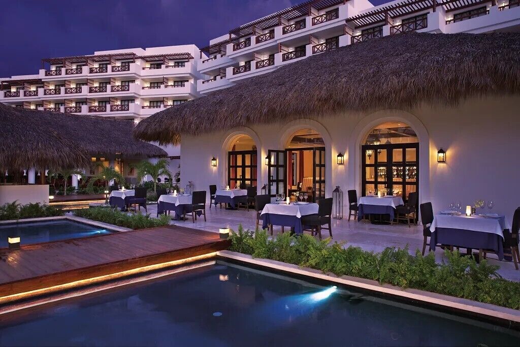 A hotel with multiple dining areas, a pool, and a thatched-roof building.