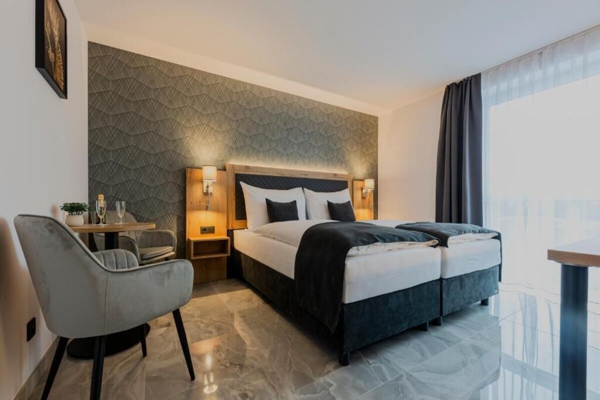 A modern hotel room with a bed, bedside tables, a chair, and a view of the city.
