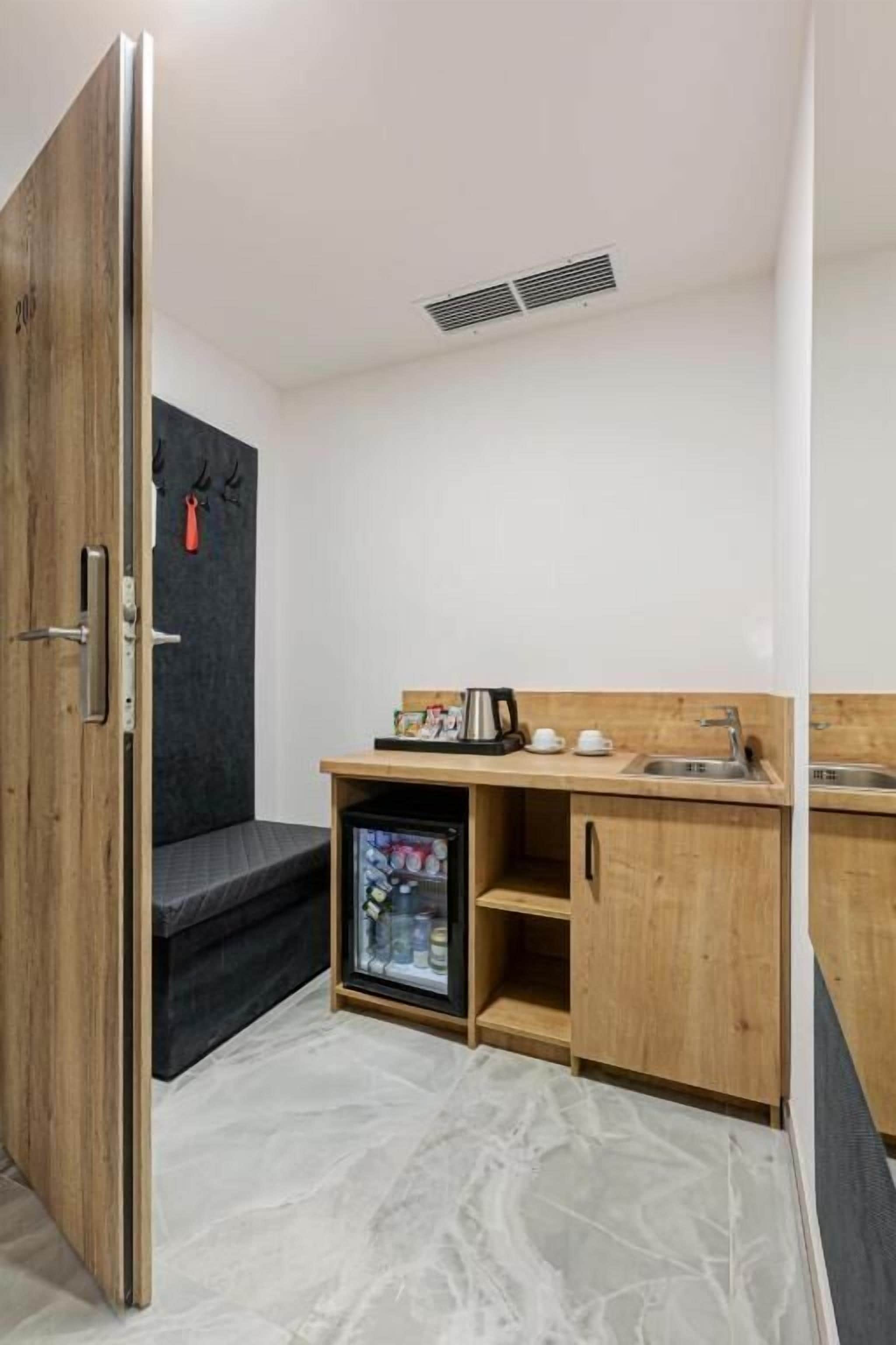 A compact kitchenette with a refrigerator, a sink, and a small countertop.