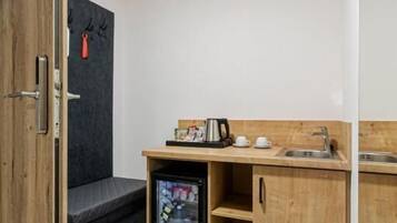 A compact kitchenette with a refrigerator, a sink, and a small countertop.