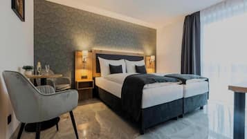 A hotel room with a bed, bedside tables, a chair, and a view of the city.