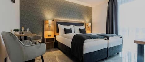 A hotel room with a bed, bedside tables, a chair, and a view of the city.