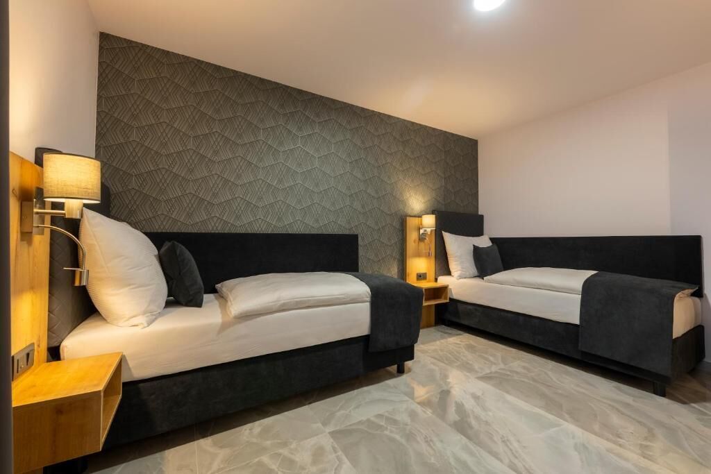 Een hotelkamer met twee bedden, een gestructureerde wand en bedlampen.