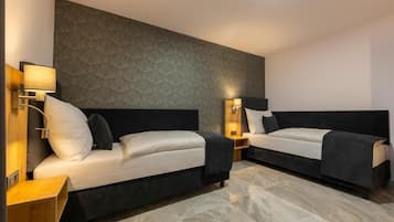 Een hotelkamer met twee bedden, een gestructureerde wand en bedlampen.