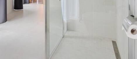 A modern bathroom with a glass-enclosed shower, a toilet, and a sink.