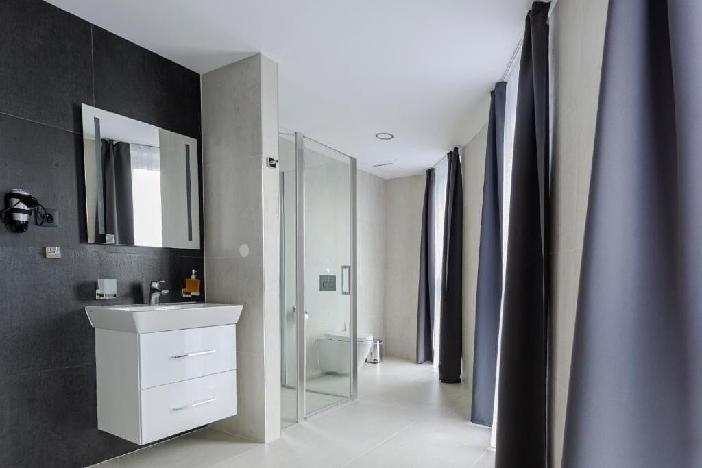 Un baño moderno con tocador blanco, cabina de ducha de vidrio y un espejo grande.