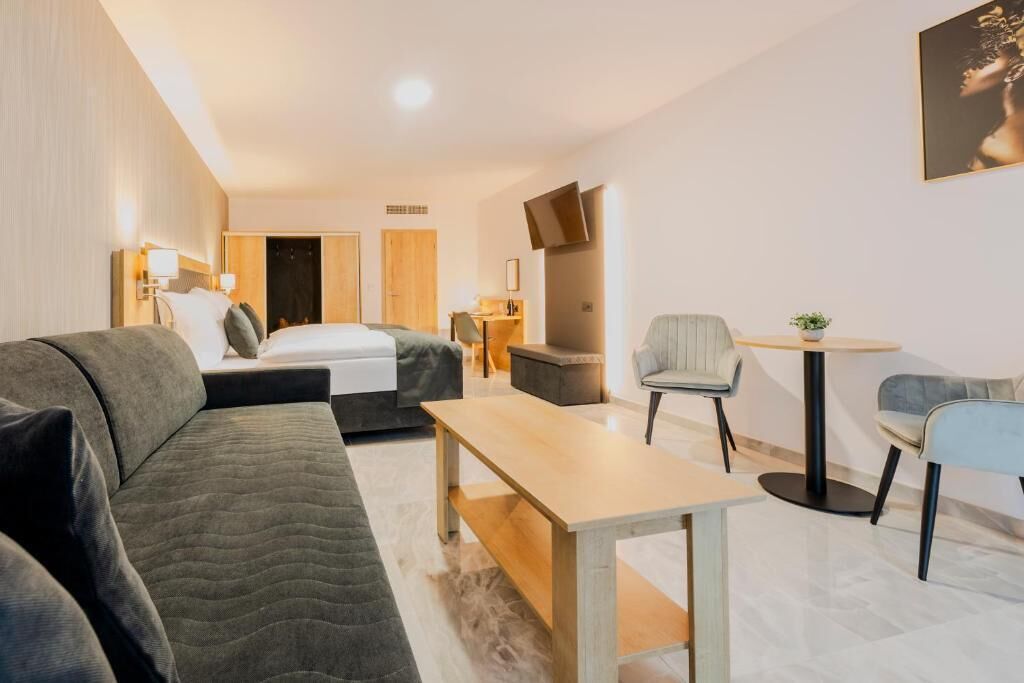 Una habitación de hotel moderna con una cama, un sofá, una mesita y una silla.