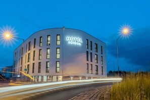 A modern hotel building with a curved facade, multiple windows, and a prominent sign.