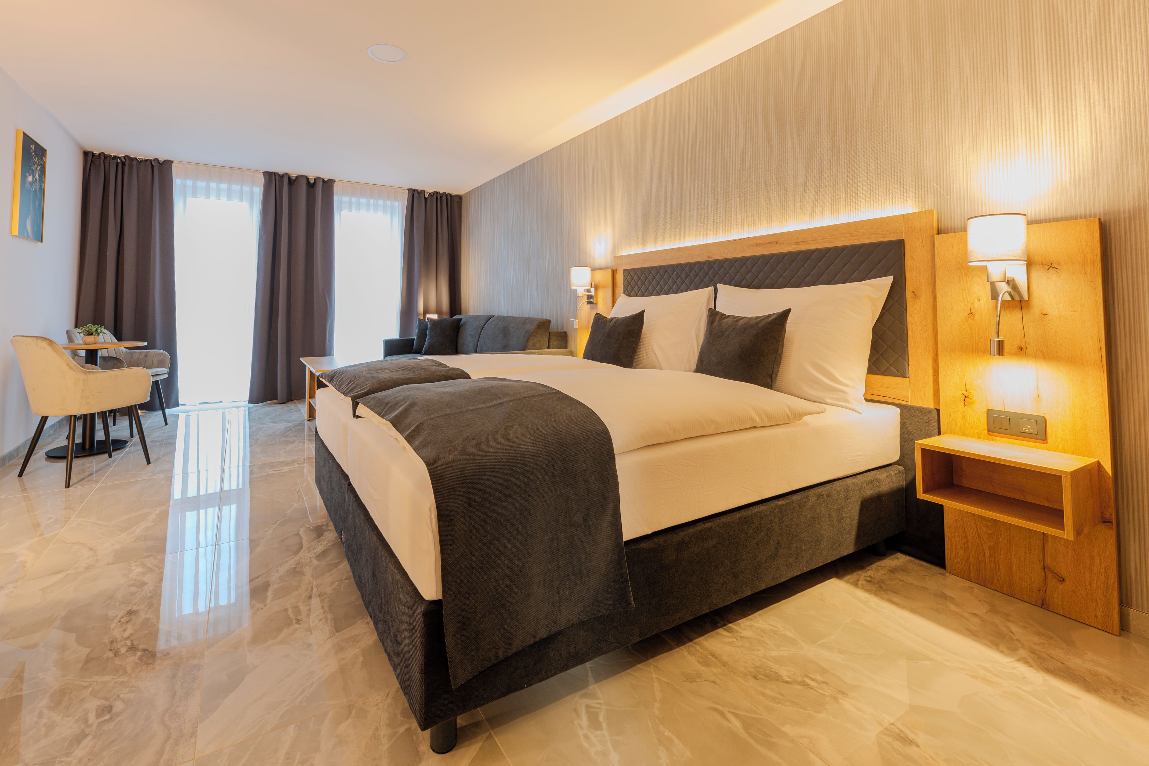 A hotel room with a large bed, bedside tables, a desk, and a chair.