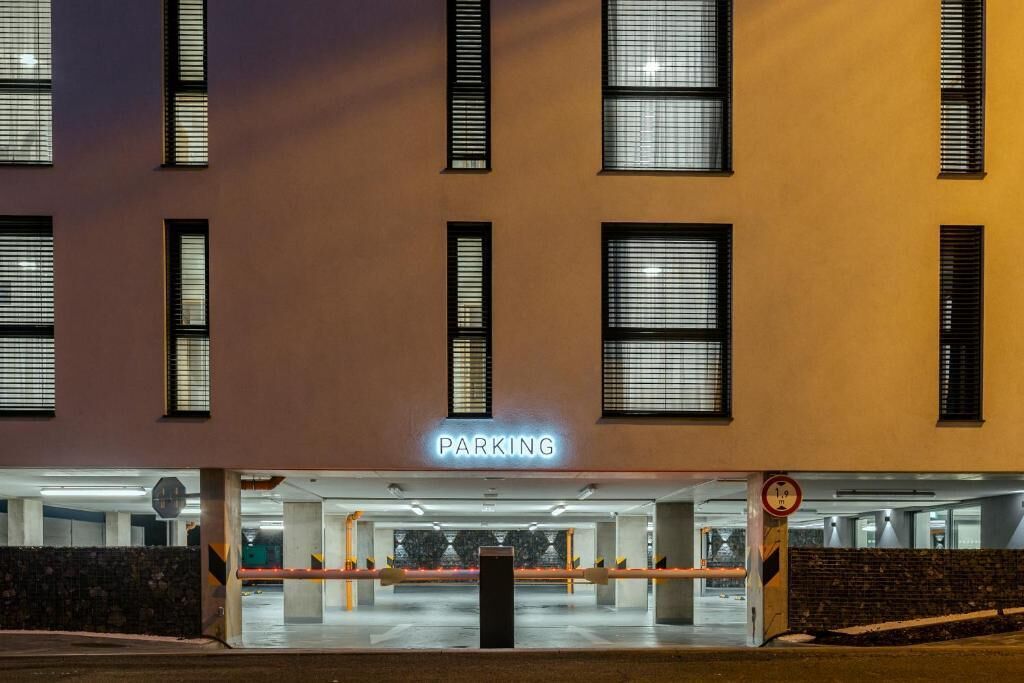 Un edificio con letrero 'PARKING', múltiples ventanas y una entrada cubierta a un estacionamiento.