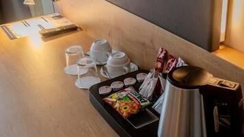 A wooden table with a tray containing a teapot, cups, and packaged snacks.