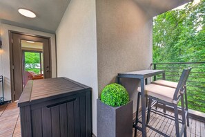 A balcony with a wooden deck, a table with a chair, and a potted plant. - The Perch | Luxury TH + Rooftop Retreat in Nature (Tracy City)