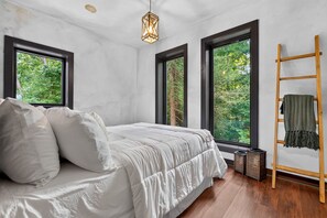A bedroom with a bed, large windows, a wooden ladder, and a hanging light fixture. - The Perch | Luxury TH + Rooftop Retreat in Nature (Tracy City)