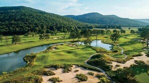A golf course with a water body, sand bunkers, and a hilly landscape. - The Perch | Rooftop Putting Green Retreat (Tracy City)