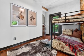 Ein Zimmer mit einem Etagenbett, einem Teppich und zwei gerahmten Bildern an der Wand.
