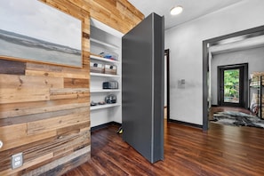 Ein modernes Interieur mit Holzvertäfelung, einer eingebauten Regaleinheit und einer dunkel gefärbten Tür.