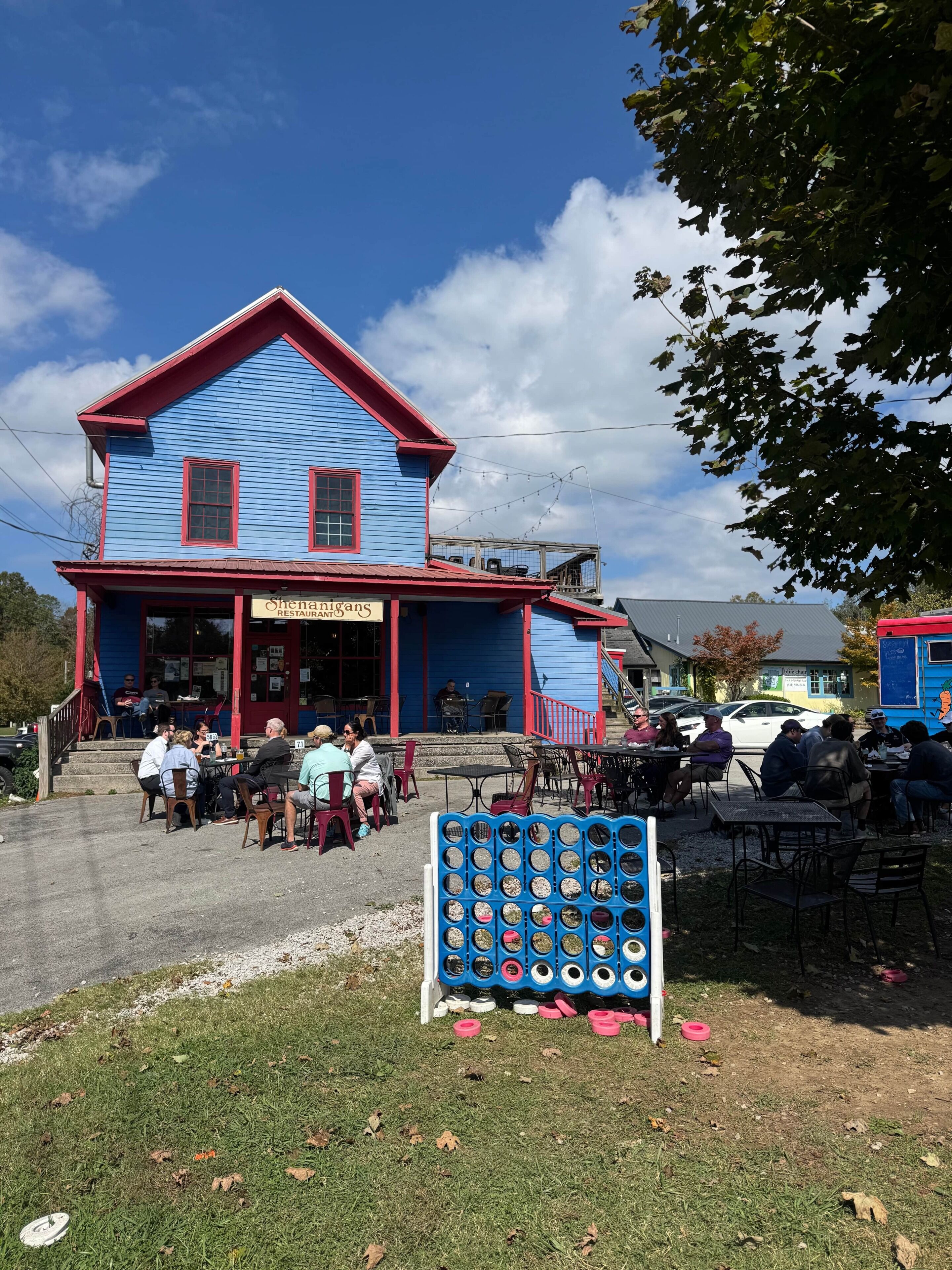 A blue building with a red roof and a sign that reads 'Shenanigans Restaurant.'