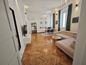 A modern living room with a herringbone floor, a beige sofa, a dining area with a table and chairs, and a kitchen in the background. - #Chic Harbor Old Town Bridge Apartment - TINELINN Apartments Zadar (Zadar)