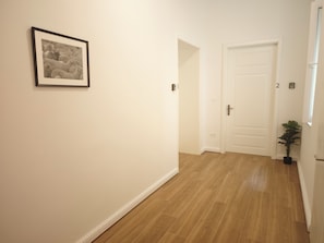 Ein Flur mit einem gerahmten Bild an der Wand, einer Tür mit einer Nummer und einem Blumentopf.