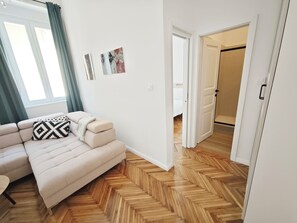 Ein modernes Wohnzimmer mit einer Couch, einem gemusterten Kissen und einem Fischgrätparkettboden.