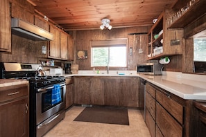 Una cocina con armarios de madera, estufa, microondas y ventana.