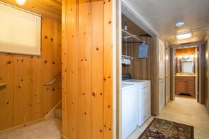 Un interior de madera con zona de lavandería, que incluye una lavadora y un tendedero.