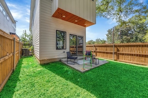 A residential backyard with a patio area, a wooden deck, and a fenced yard. - Modern 3BR Walk to Fair Park - EV Ready & Yard (Dallas)