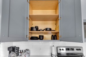 A kitchen with grey cabinets, a coffee maker, and a stove. - Modern 3BR Walk to Fair Park - EV Ready & Yard (Dallas)