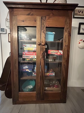 A wooden cabinet with glass doors containing board games and storage bins. -  Farmhouse in Windsor. A scenic countryside escape. (Windsor)