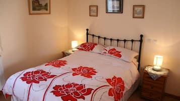 Une chambre à coucher avec un lit, deux tables de chevet et des tableaux accrochés au mur.