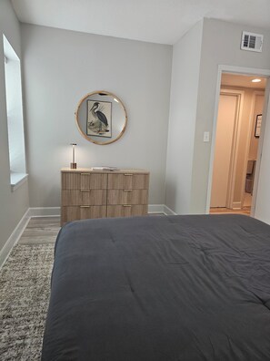 A bedroom with a bed, a dresser, a framed picture on the wall, and a window. - Cozy 1-bedroom apartment in charming KC's 'Squire Park with in-unit washer/dryer (Kansas City)