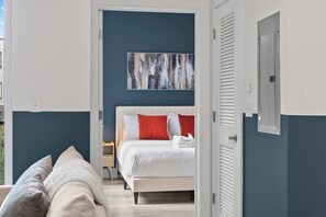 A bedroom with a bed, a nightstand, and a painting on the wall. - Chic 1BR Stay | Sleeps 4 | Northern Liberties (Philadelphia)
