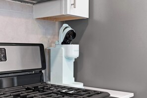 A kitchen with a built-in grill, a white cabinet above it, and a grey wall. - Chic 1BR Stay | Sleeps 4 | Northern Liberties (Philadelphia)