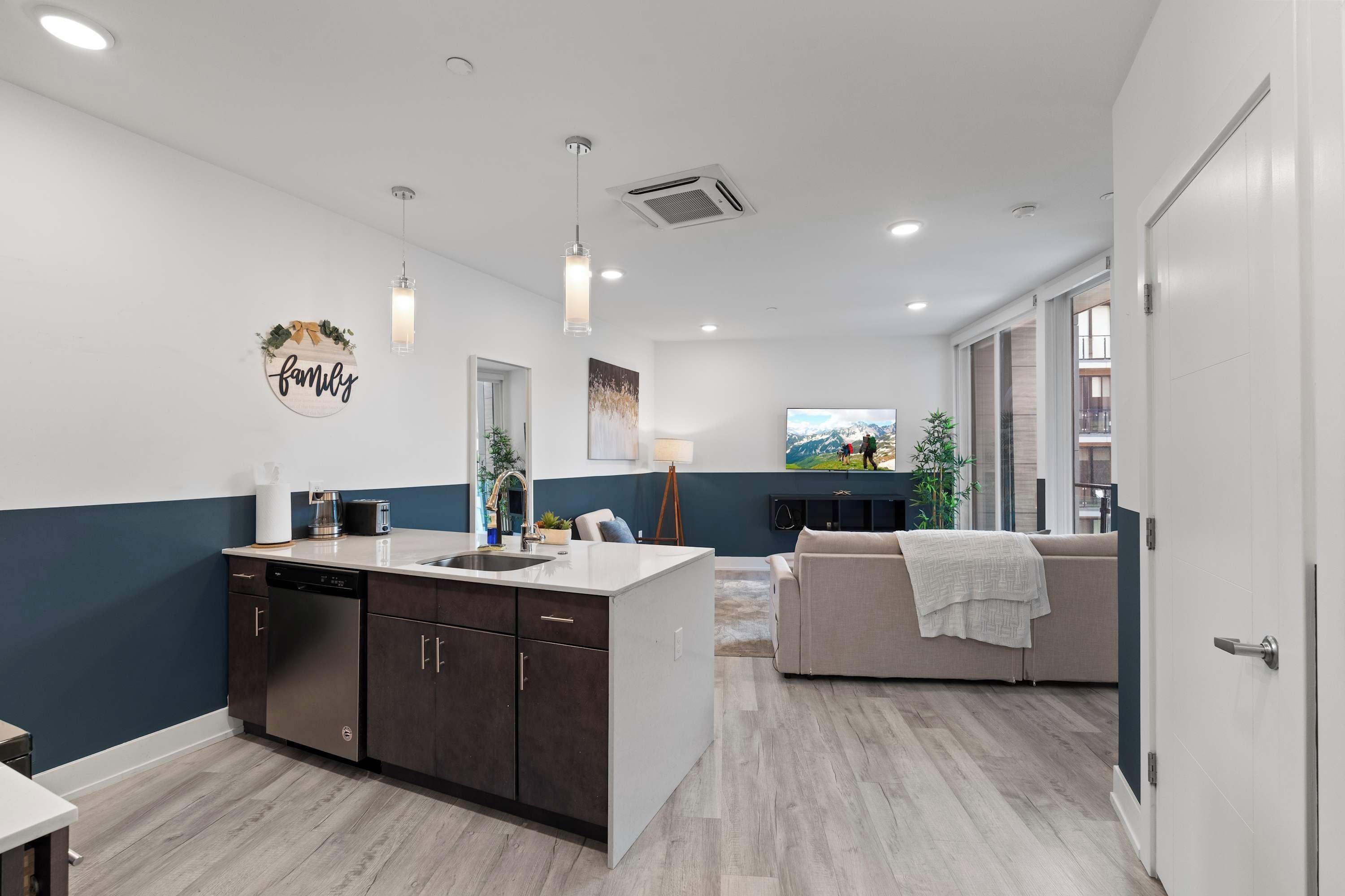 A modern kitchen with a central island, a dining area with a sofa, and a living room with a TV.