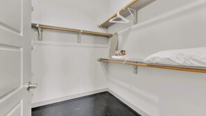 A hotel room with a bed, a small shelf with toiletries, and a door. - Modern Uptown 1BR | Sleeps 4 | Near Klyde Park (Dallas)