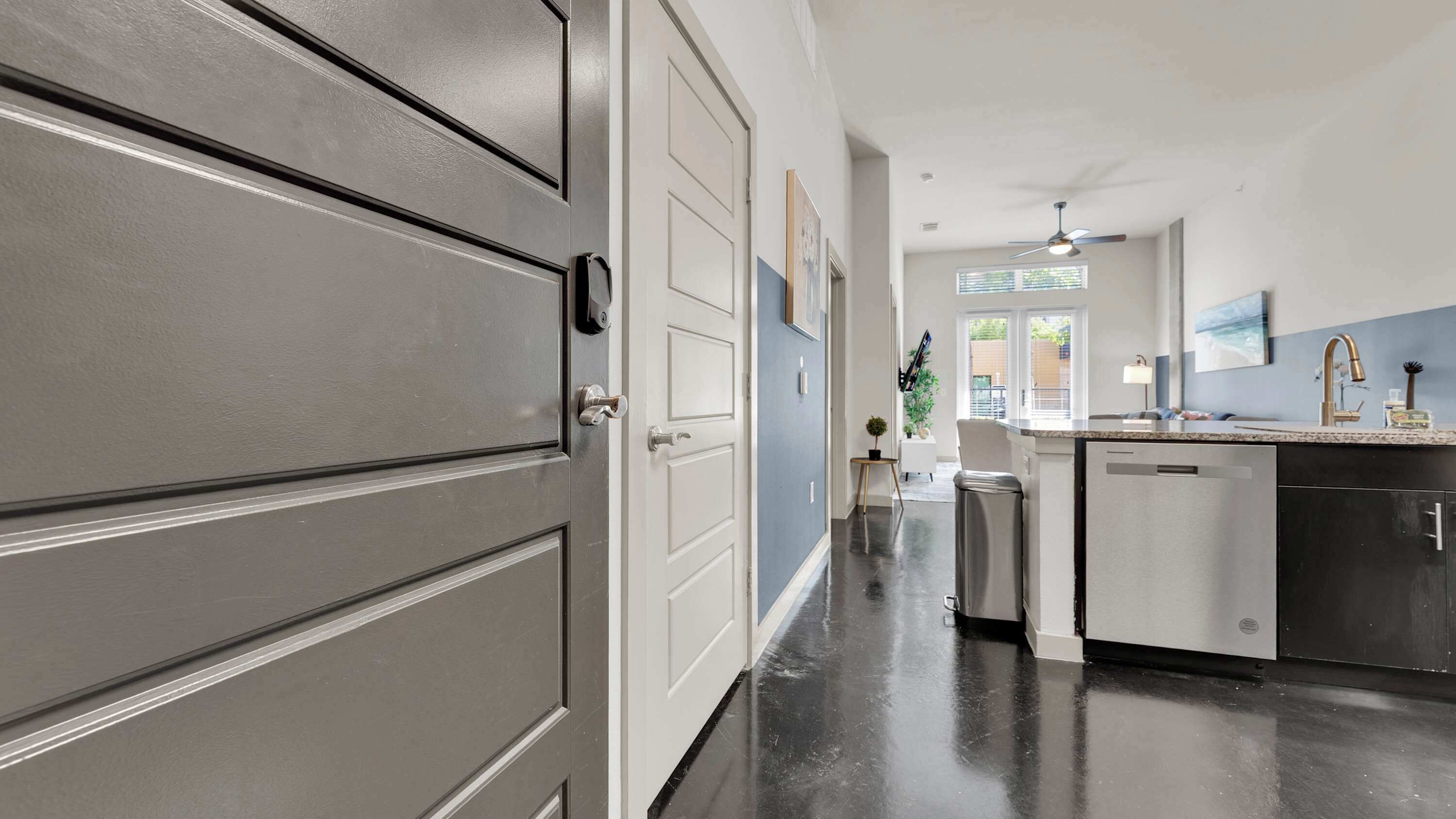 A modern kitchen with a central island, stainless steel appliances, and a view to the outside.