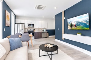 A modern living room with a sofa, coffee table, and a TV mounted on the wall. - Fresh 1BD Near City Hall | Comfortably Sleeps 2 (Philadelphia)